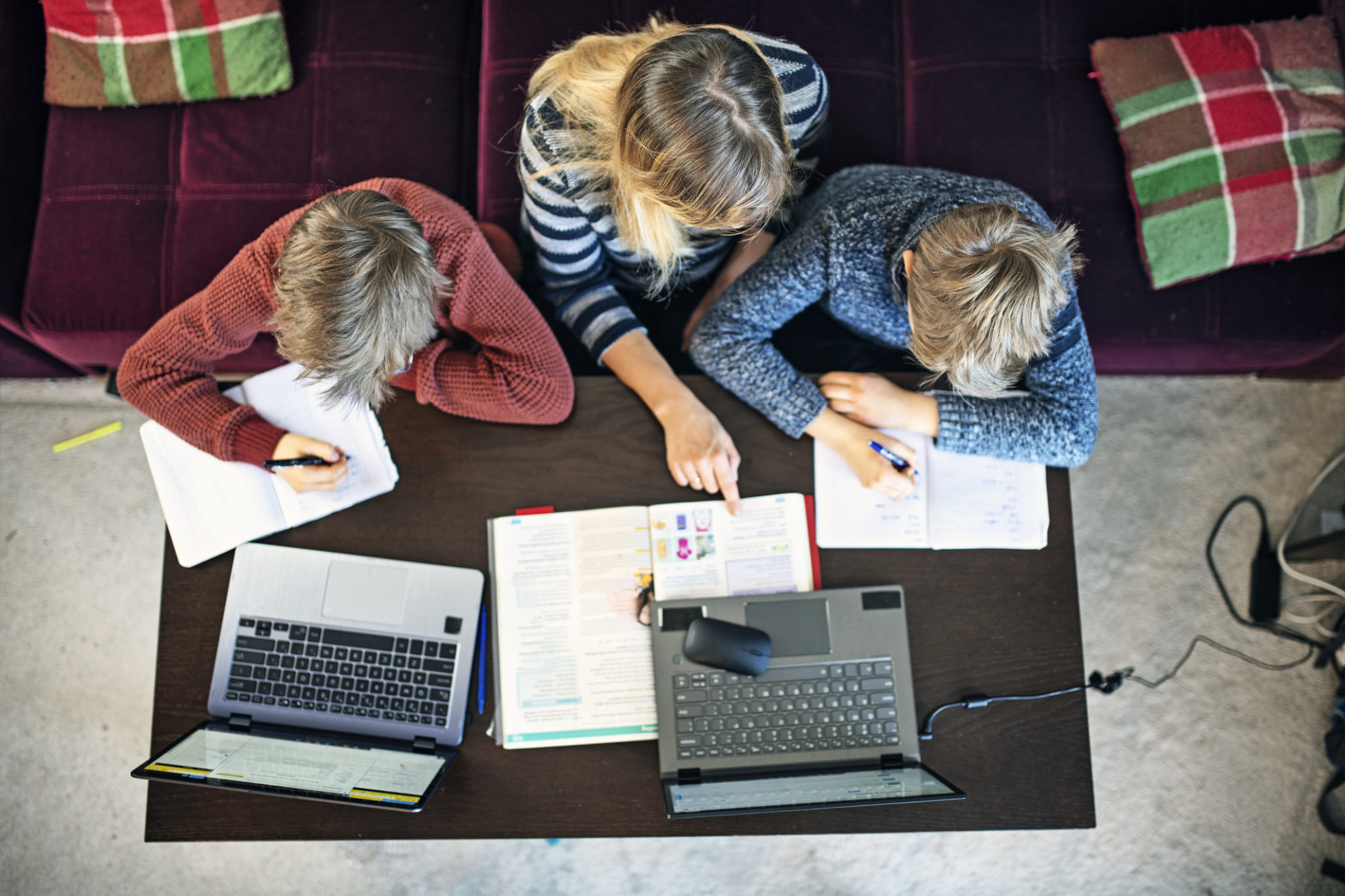 Two students get homeschooling help from parent