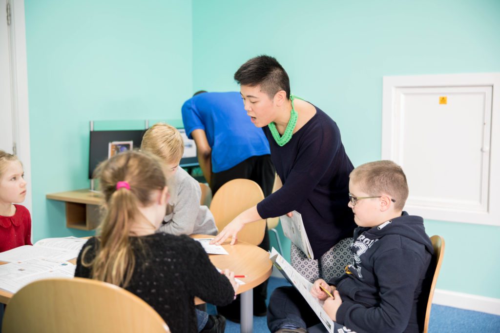 Tutor helping a group of students sitting at a table