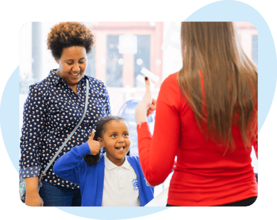 A young girl excitedly gives a thumbs up to her tutor in front of mum