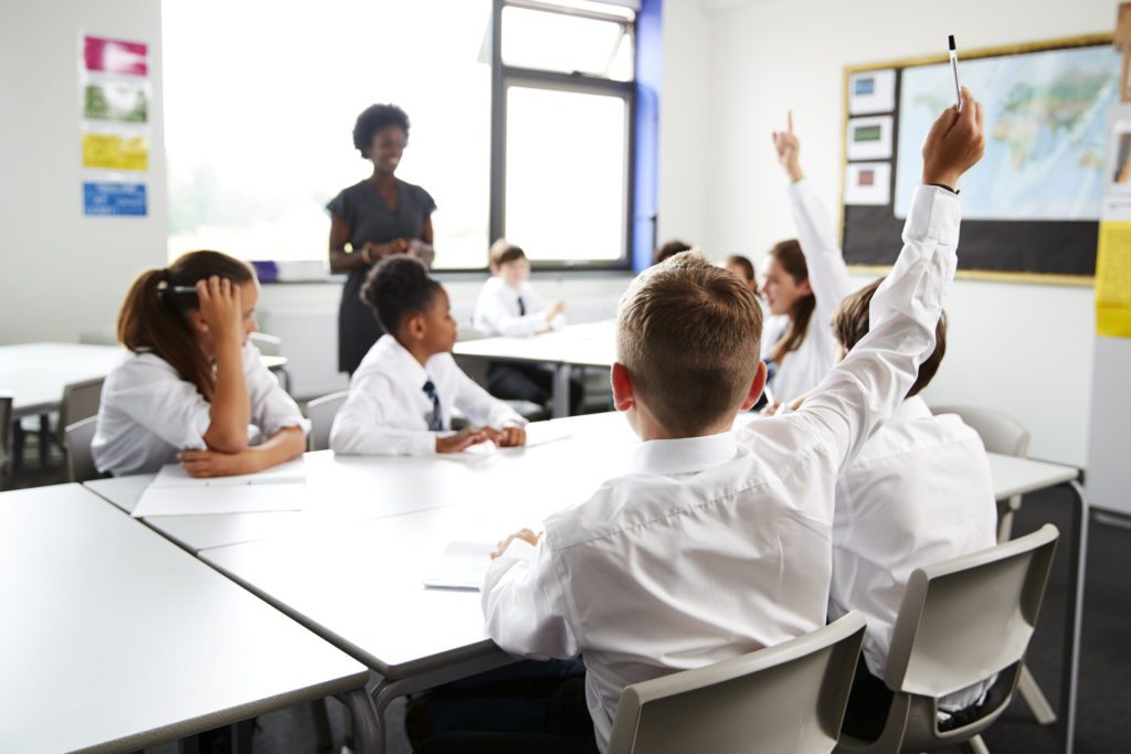 Students raising their hands to answer a question in the classroom