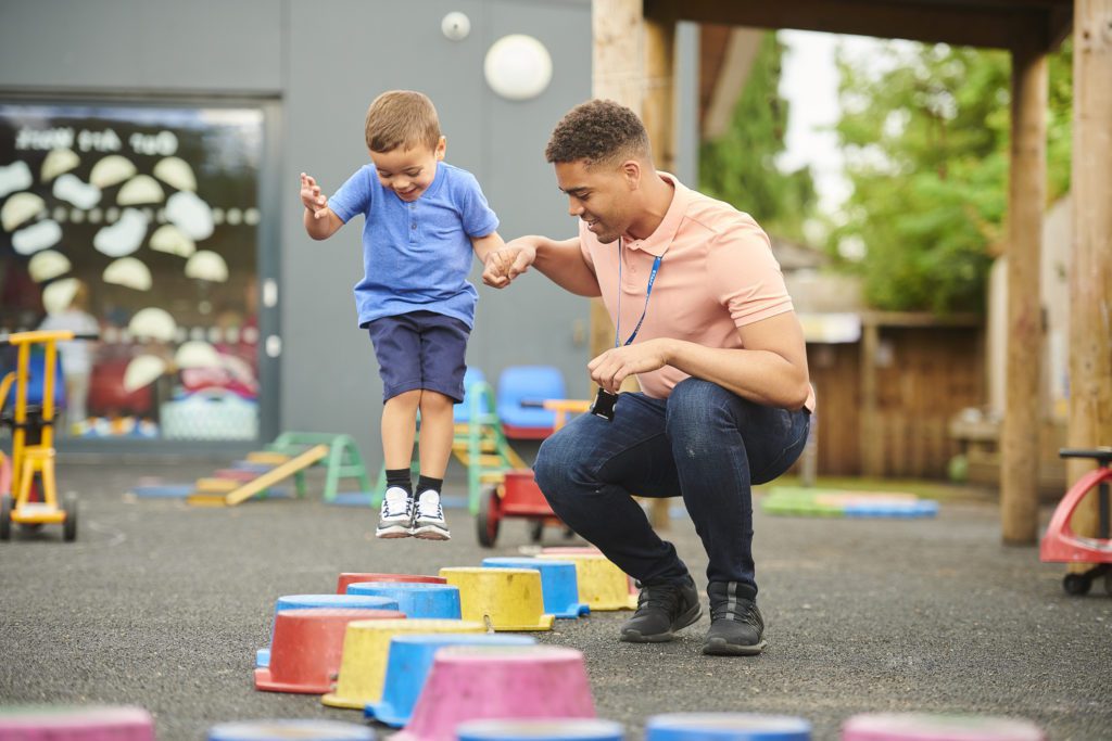 A mentor playing with a child in a playground
