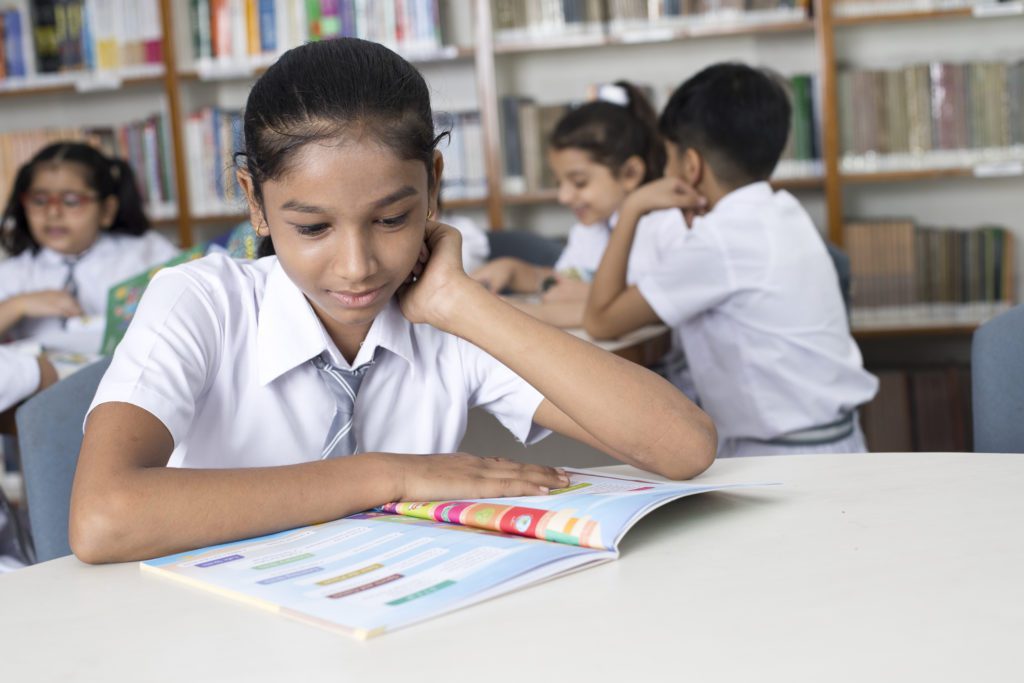 A school aged girl reading about 11 Plus vocabulary in the classroom