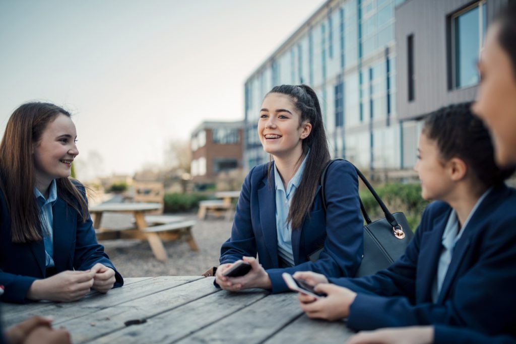 Children smiling around a table in the playground