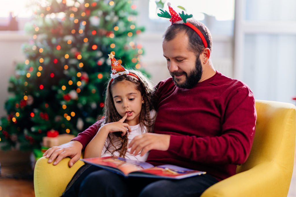 Father and daughter read by the Christmas tree