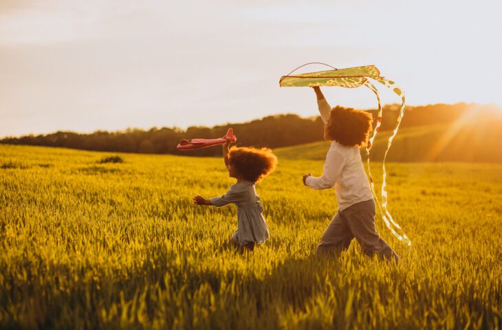Two children playing with kites in a field during half term